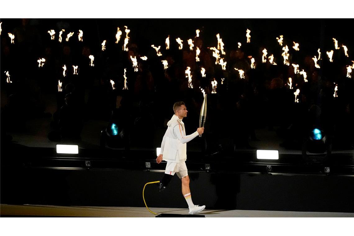 Der deutsche Athlet Markus Rehm trägt die Fackel während der Eröffnungsfeier für die Paralympics 2024 in Paris.