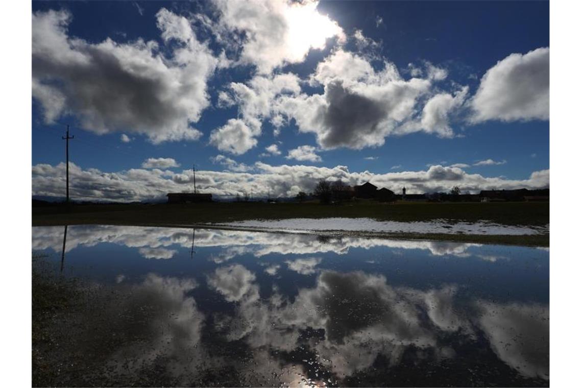 Bunter Wetter-Mix mit Wolken, Wind und Sonne Der Himmel und die Allgäuer Landschaft spiegeln sich in einem See aus getautem Schnee. Foto: Karl-Josef Hildenbrand/dpa