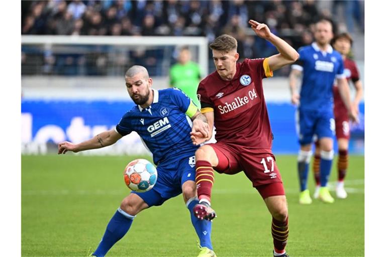 Der Karlsruher Jerome Gondorf (l) und der Schalker Florian Flick kämpfen um den Ball. Foto: Uli Deck/dpa