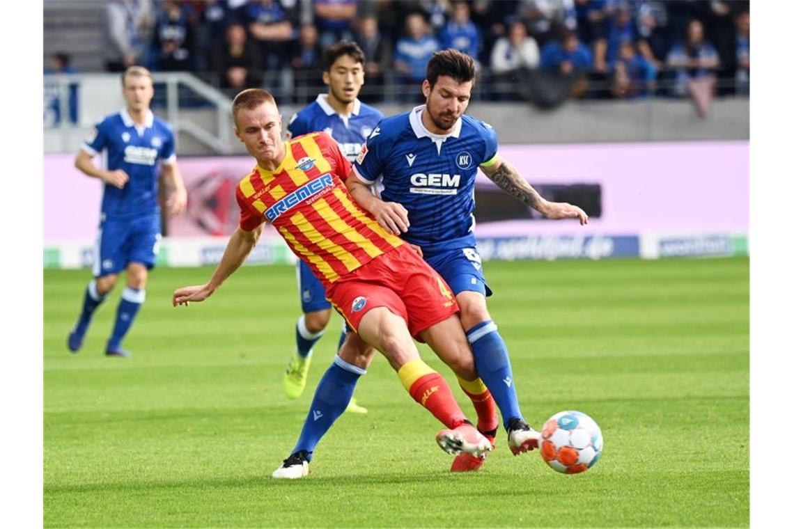 Der Karlsruher Jerome Gondorf (r) und der Paderborner Jasper van der Werff kämpfen um den Ball. Foto: Uli Deck/dpa