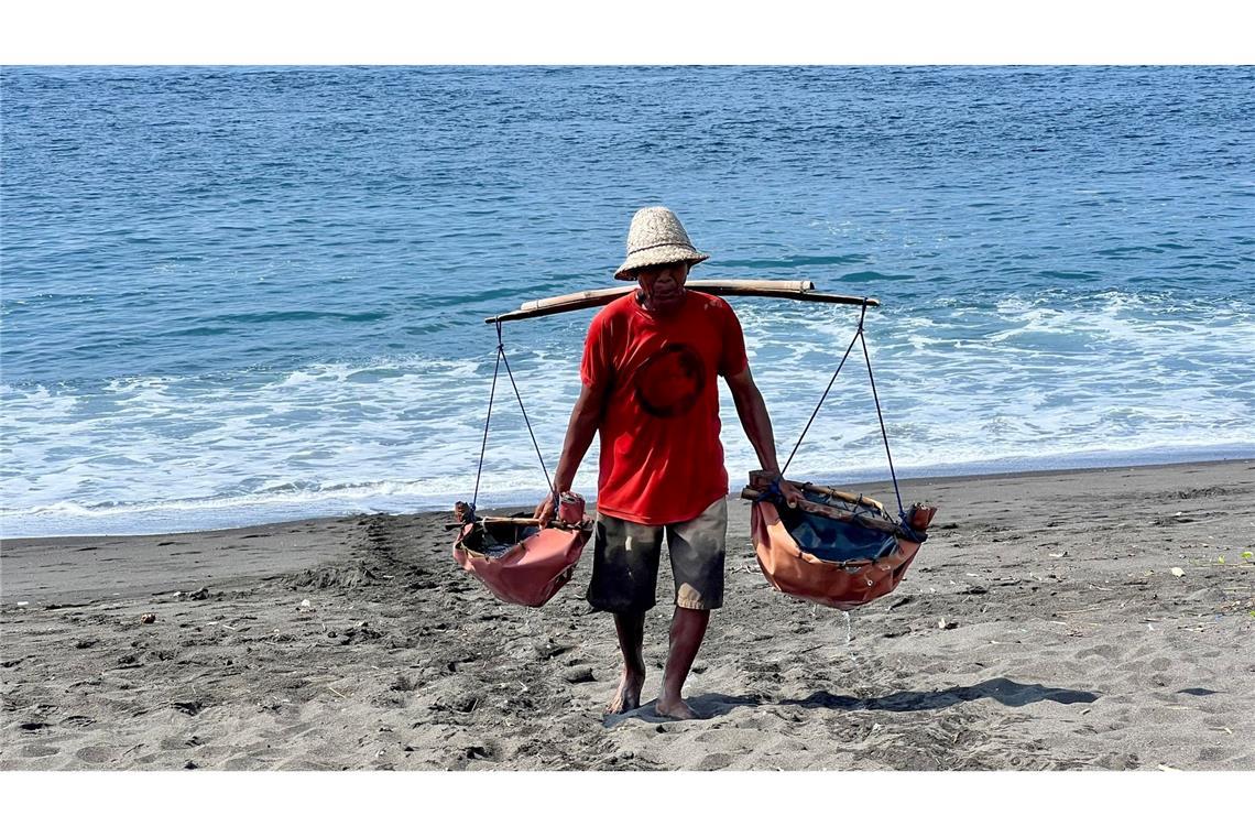 Der Salzbauer Nyoman Warta schleppt Meerwasser an den Strand. Er ist einer der letzten Vertreter dieses Berufs auf der indonesischen Urlaubsinsel.