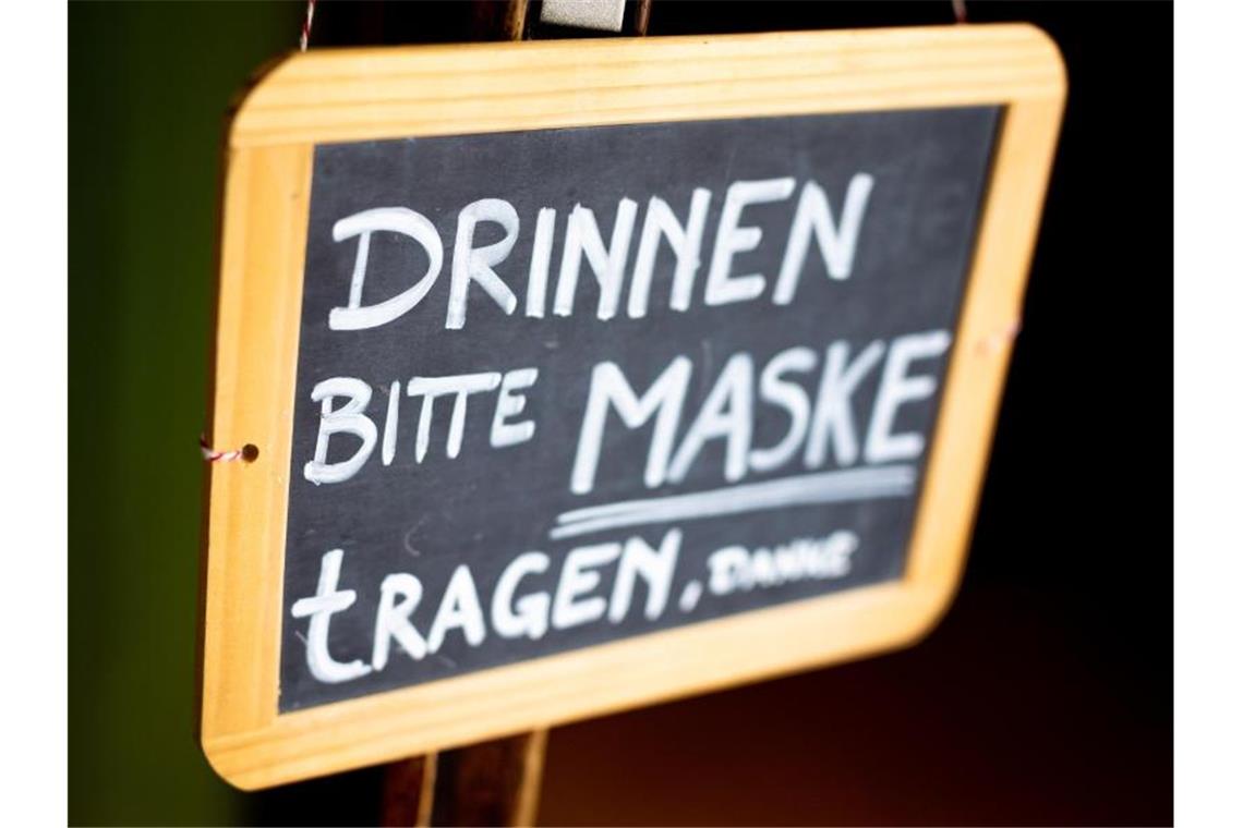 Der Schrifzug „Drinnen bitte Maske tragen, danke“ ist auf dem Schild eines Restaurants zu lesen. Foto: Moritz Frankenberg/dpa