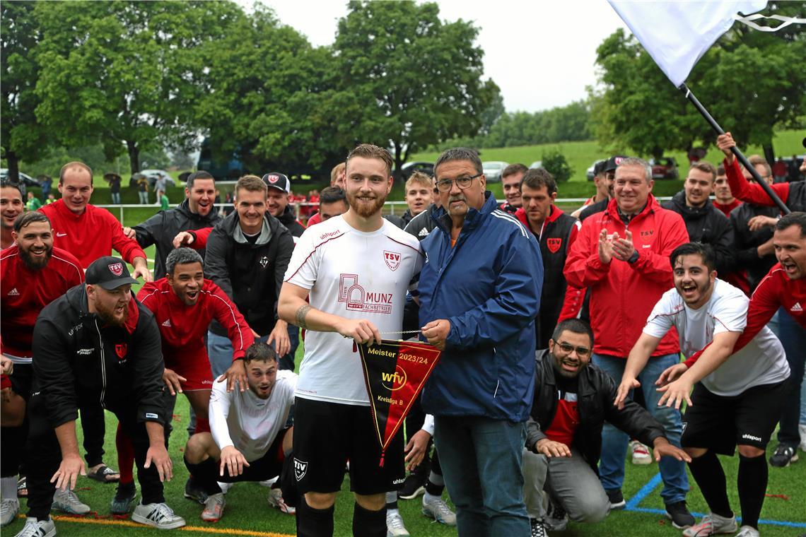 Der TSV Oberbrüden und sein Coach Roberto Sadler (rote Jacke, rechts) jubeln. Staffelleiter Jochen Seiler überreicht Kapitän Paul Aspacher den Meisterwimpel. Dank seiner zweiten Mannschaft ist der Verein aus Auenwald zurück in der Kreisliga A. Foto: Bernd Strohmaier