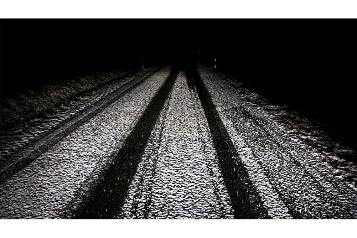 Der Winter beginnt. Reifenspuren sind am Abend auf einer mit Schnee überzogenen Nebenstraße zu sehen.