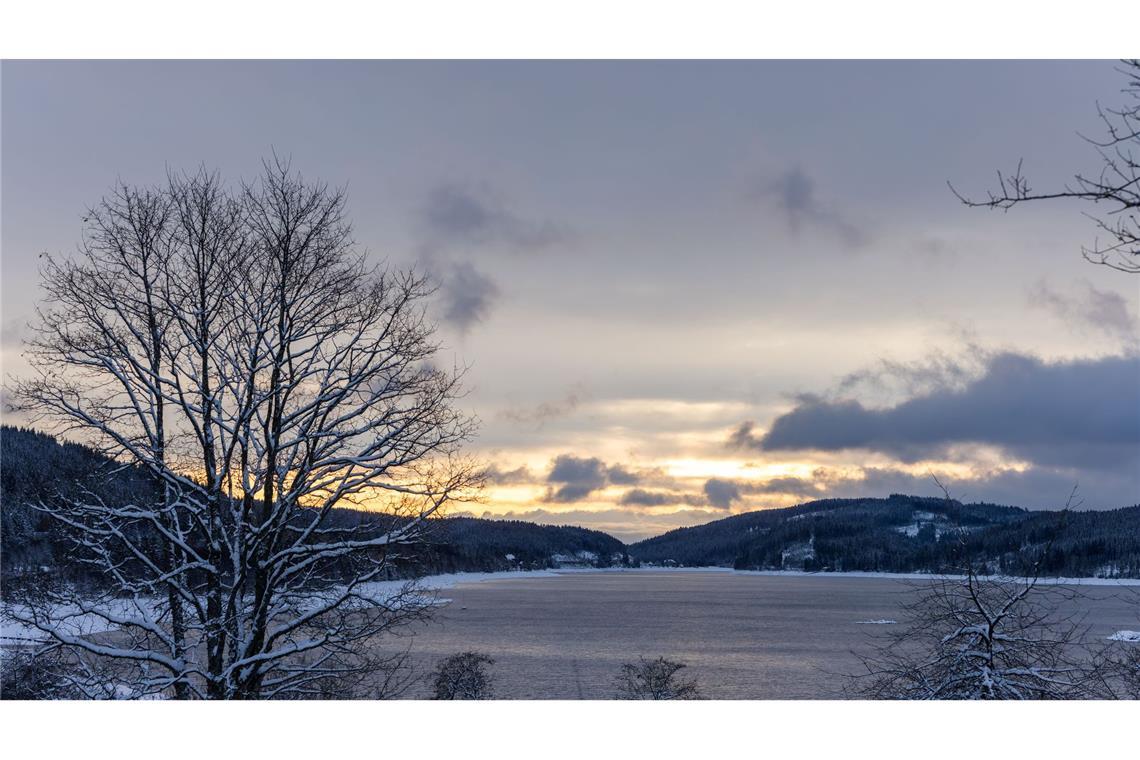 Die aufgehende Sonne beleuchtet den Himmel über dem Schluchsee  in Baden-Württemberg.