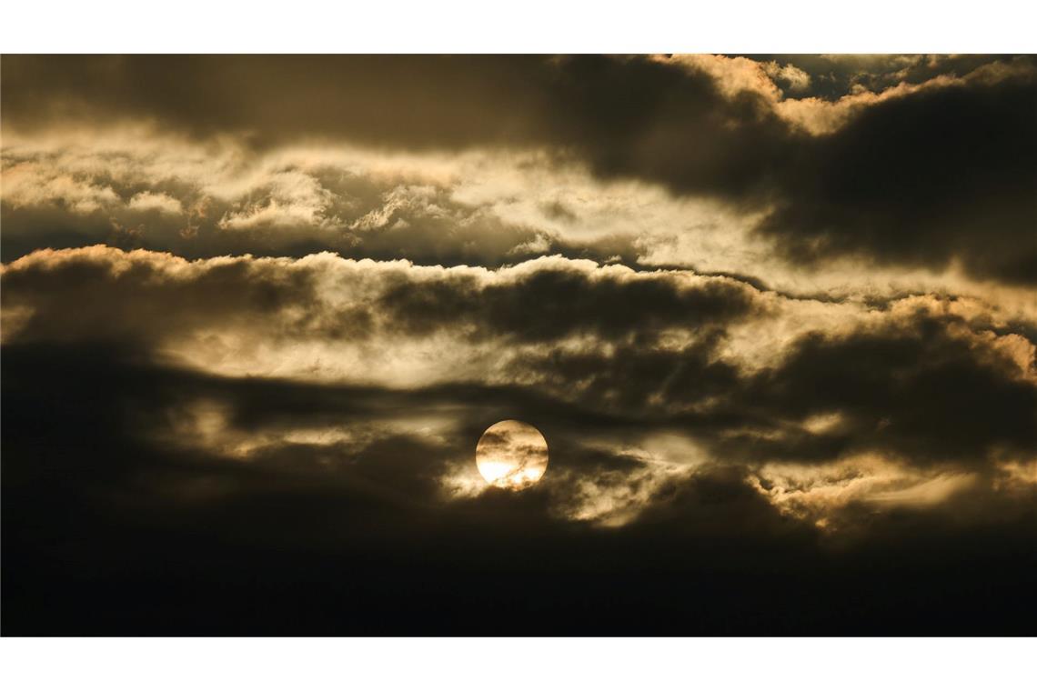 Die aufgehende Sonne kommt am Morgen hinter den Wolken in Berlin hervor.