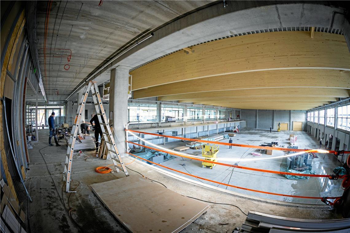 Die Dachträger aus Lärchenholz sind ein Blickfang in der neuen Sporthalle. Rund 50 Handwerker sind hier derzeit mit dem Innenausbau beschäftigt. Solange der Sportboden noch nicht eingebaut ist, kommen dabei auch Hebebühnen zum Einsatz. Fotos: Alexander Becher