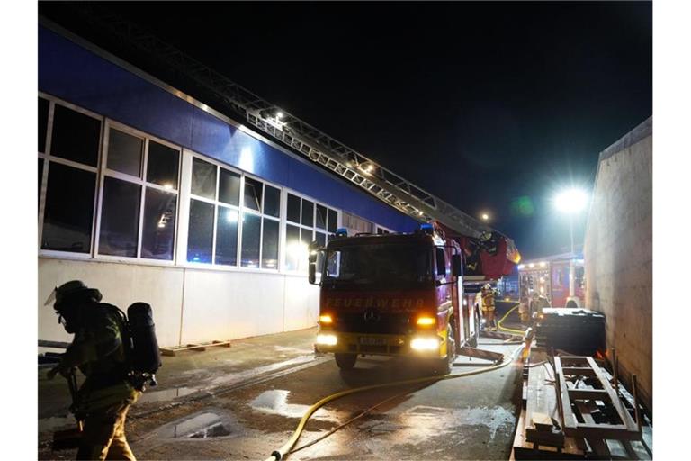 Die Feuerwehr bekämpft einen Brand in einer Lagerhalle. Foto: Andreas Rosar/dpa