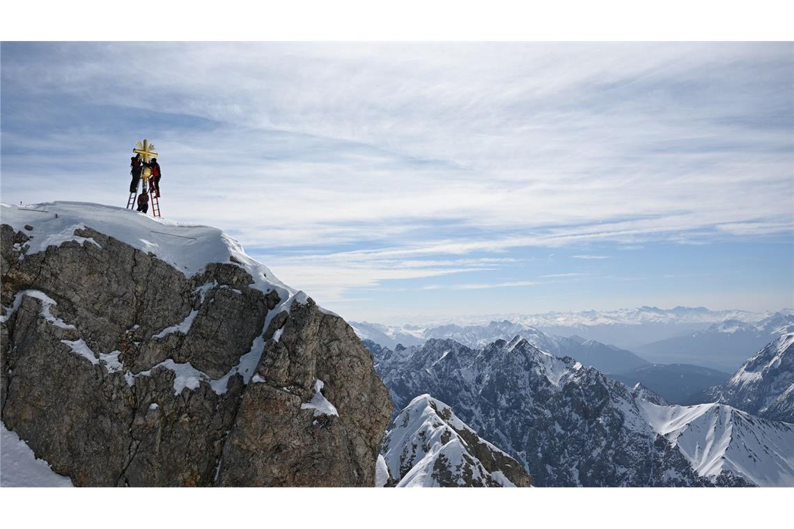 Die im Tal restaurierten Strahlen des Gipfelkreuzes der Zugspitze werden von Mitarbeitern wieder angebracht.