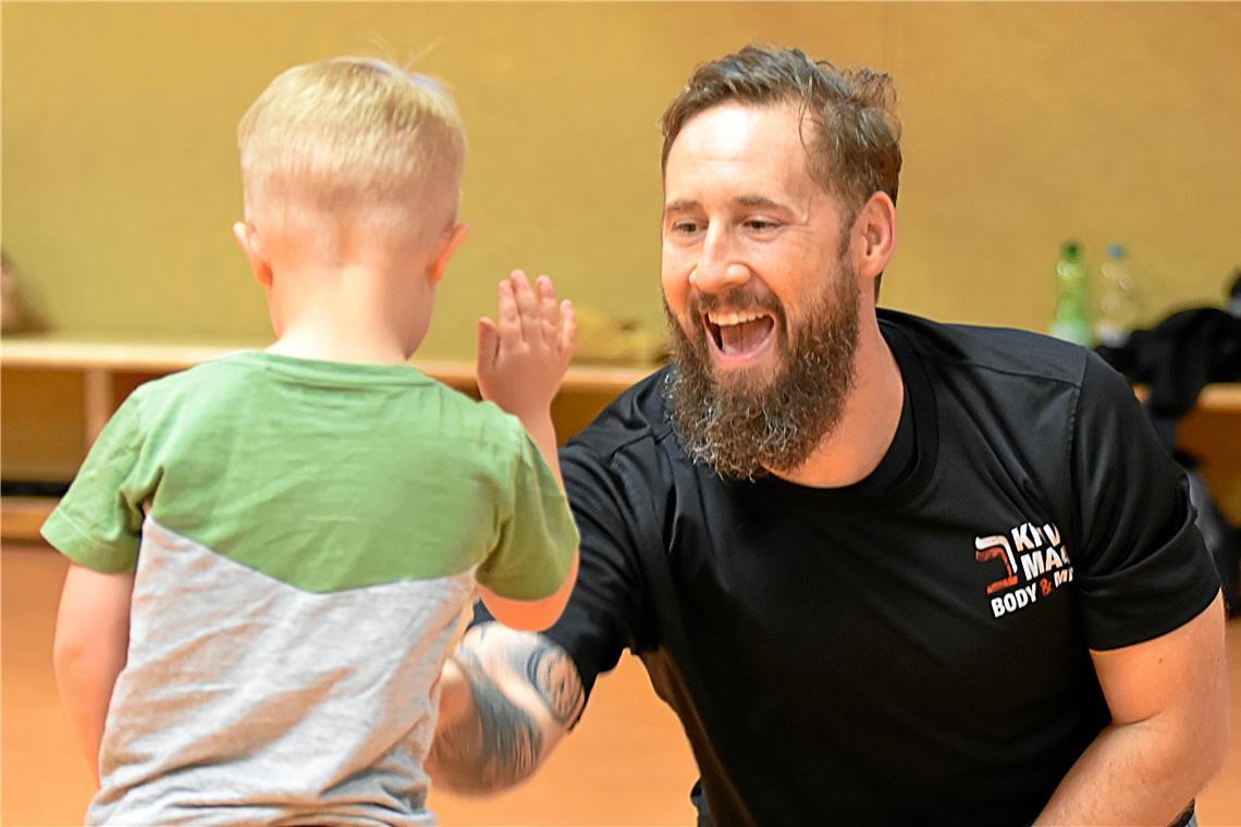 Die Kinder lernen, eine Hand abzuwehren. Auch wenn es im Spiel nur die Hand ihres Trainers Felix Remppel ist. Bei dieser Übung geht es darum, eine Wäscheklammer vom Shirt des Kindes wegzunehmen. Das Kind darf oder soll sich sogar wehren. Foto: Tobias Sellmaier