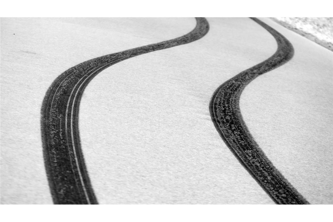 Die Kurve gekriegt: Reifenspuren zeichnen sich auf einer Straße in Südbayern im Neuschnee ab.