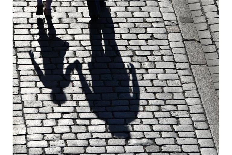 Die Schatten einer erwachsenen Person und eines Kindes sind zu sehen. Foto: Matthias Hiekel/ZB/dpa/Symbolbild