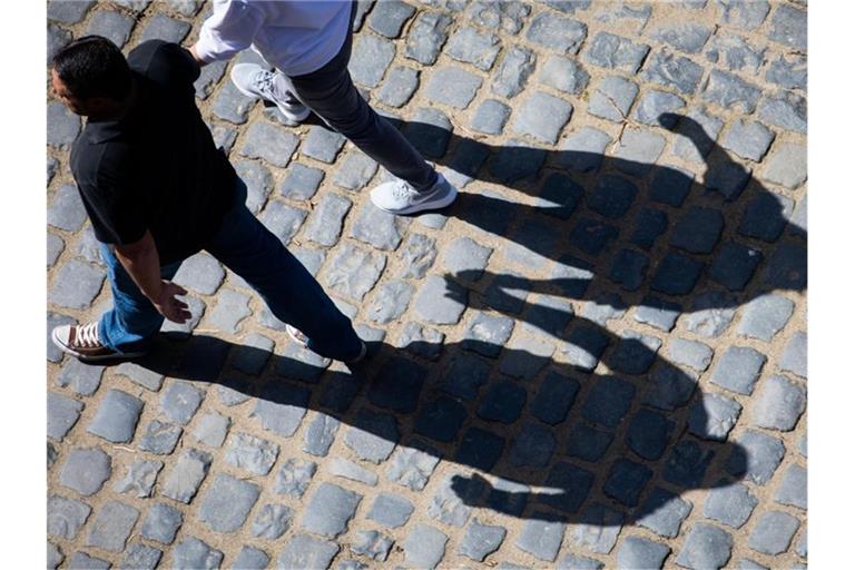 Die Schatten zweier Menschen, die Hand in Hand gehen, zeichnet sich auf dem Pflaster des Schlosses Auerbach ab. Foto: Frank Rumpenhorst/dpa