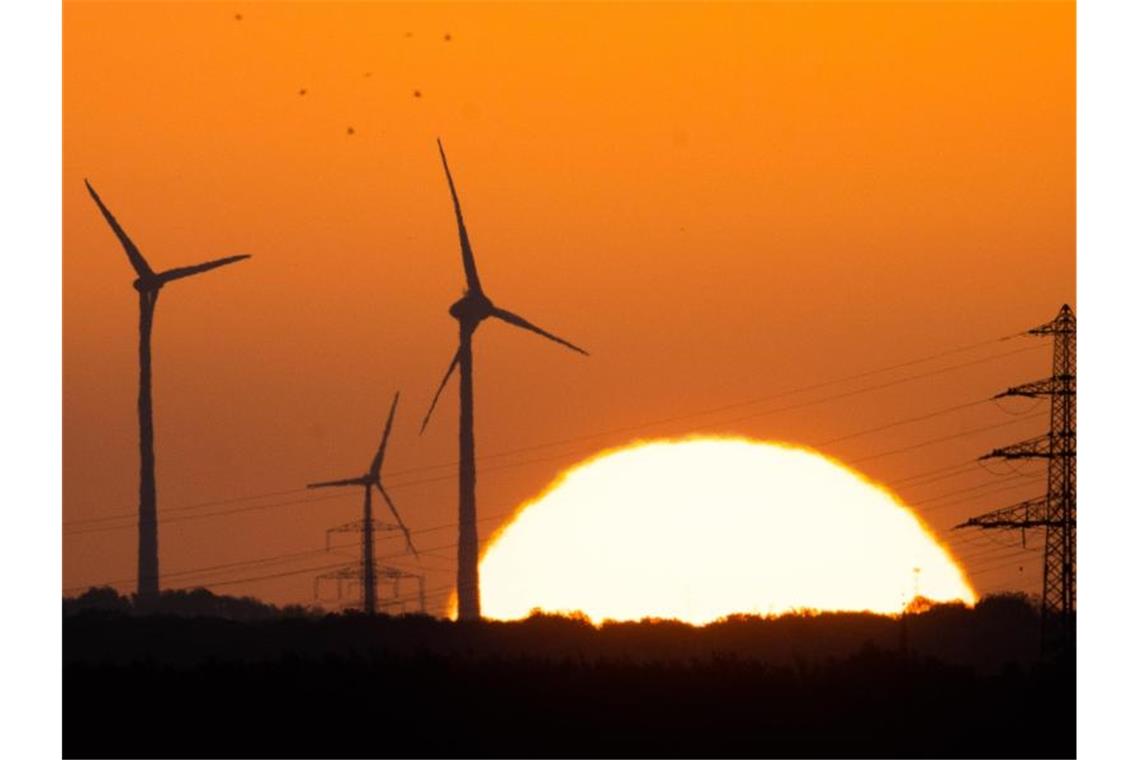 Die Sonne geht hinter Windrädern und Hochspannungsleitungen auf. Foto: Julian Stratenschulte/dpa/Symbolbild