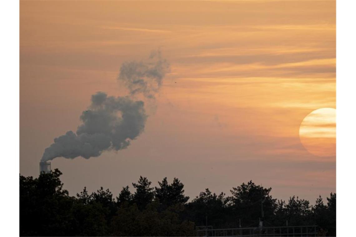 Strengere Schadstoff-Grenzwerte für Industrie und Bauern Die Sonne geht neben einem rauchenden Schornstein unter. Die Grenzwerte für den Ausstoß von Schadstoffen aus vielen Industrieanlagen werden strenger. Foto: Fabian Sommer/dpa