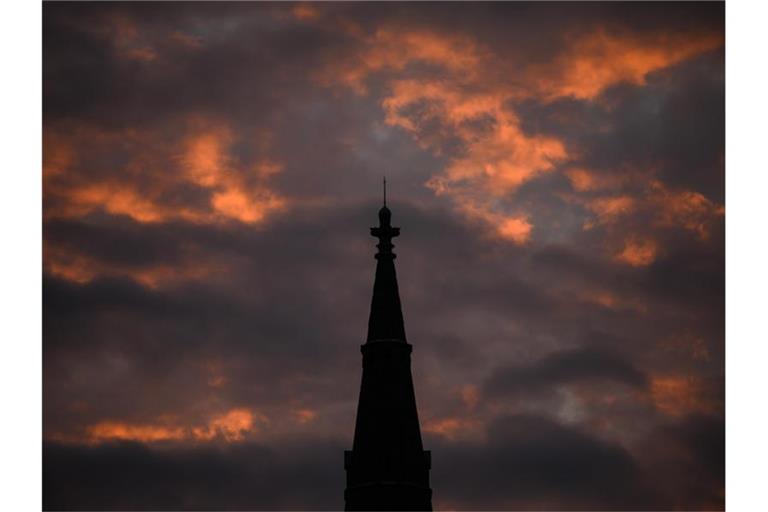 Die Sonne strahlt am Morgen die Wolken hinter der Matthäuskirche in Stuttgart an. Foto: Sebastian Gollnow/dpa/Archivbild