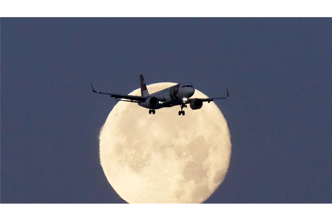 Dieses Flugzeug lässt die Nacht hinter sich. Ein Airbus A320 der TAP Air Portugal hebt sich bei Sonnenaufgang im Landeanflug auf Lissabon gegen den untergehenden Mond ab.