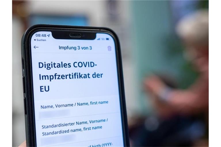 "Digitales Covid-Impfzertifikat der EU" steht auf einem Handy in einem Friseursalon. Foto: Armin Weigel/dpa/Symbolbild