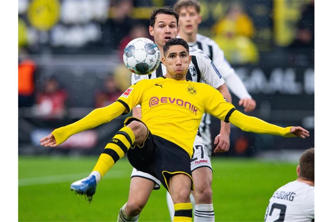 Mit Mühe und Glück: Dortmund schlägt Freiburg 1:0 Dortmunds Achraf Hakimi (vorne) schießt den Ball gegen Freiburgs Nicolas Höfler (hinten) aufs Tor. Foto: Guido Kirchner/dpa