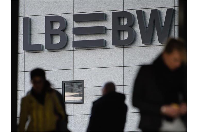 Drei Menschen gehen vor dem Schriftzug der Landesbank Baden-Württemberg (LBBW) entlang. Foto: Sebastian Gollnow/dpa