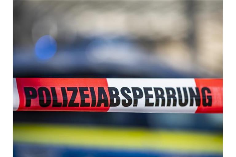 Ein Absperrband mit der Aufschrift „Polizeiabsperrung“ ist vor einem Polizeiwagen aufgespannt. Foto: David Inderlied/dpa/Illustration