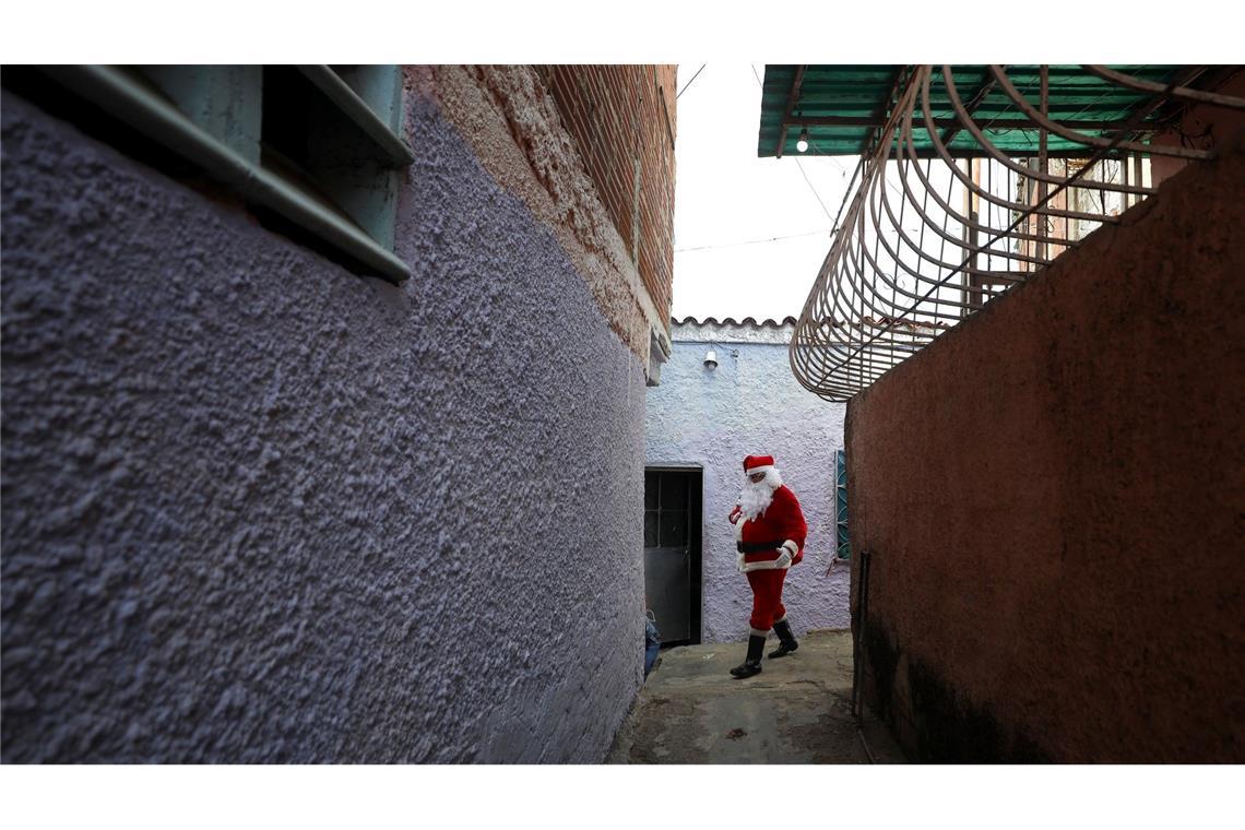 Ein als Weihnachtsmann verkleideter Mann verteilt Spielzeug an Kinder in einem als "COTA 905" bekannten Armenviertel in Caracas.