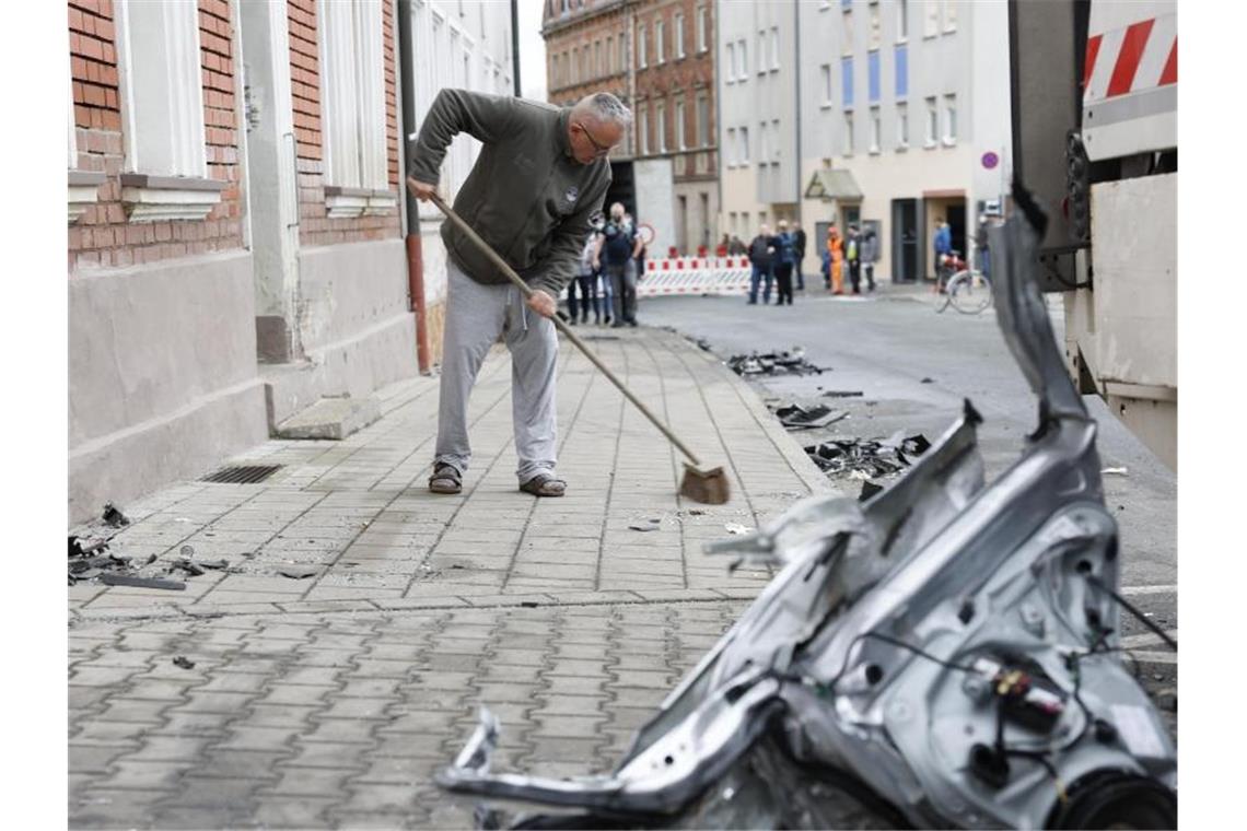 Weiter Ursachenforschung nach Verwüstungs-Fahrt in Fürth Ein Anwohner kehrt am Tag nach der Chaosfahrt den Bürgersteig vor seinem Haus. Foto: Löb Daniel/dpa