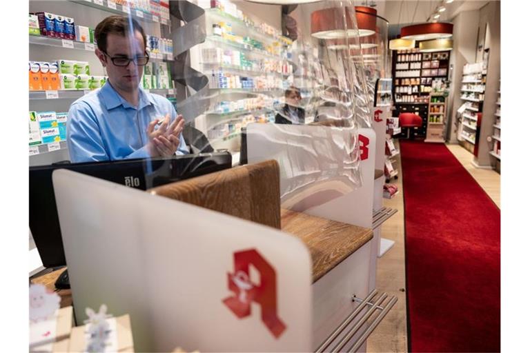 Ein Apotheker desinfiziert sich hinter einer Plexiglasscheibe die Hände. Foto: Bernd Thissen/dpa/Archivbild