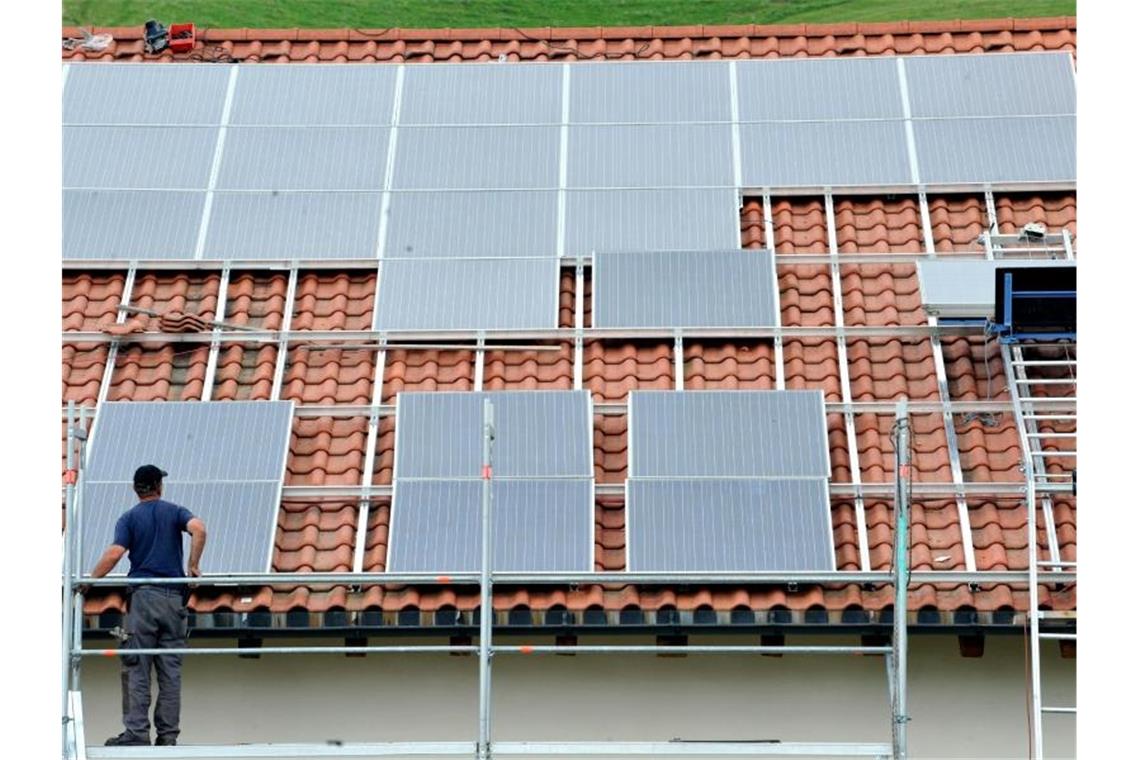 Ein Arbeiter installiert auf einem Dach eine Solaranlage. Foto: Rolf Haid/dpa/Archivbild