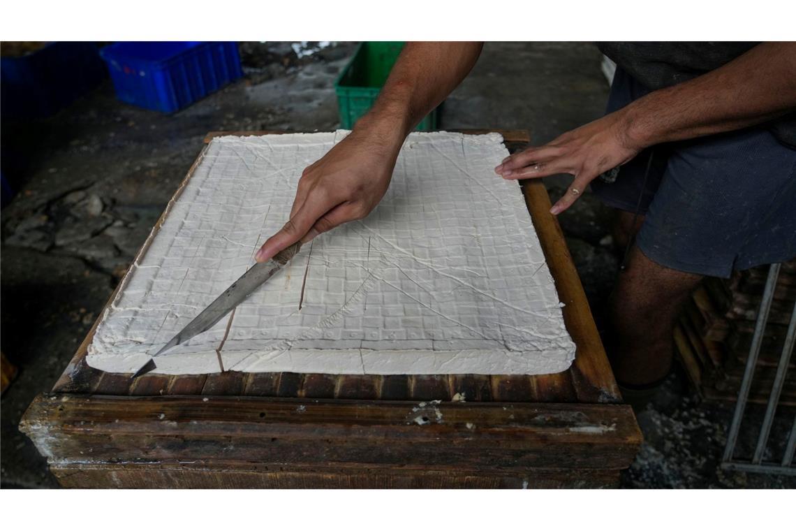 Ein Arbeiter schneidet traditionellen Tofu in einer Heimfabrik am Stadtrand von Jakarta.