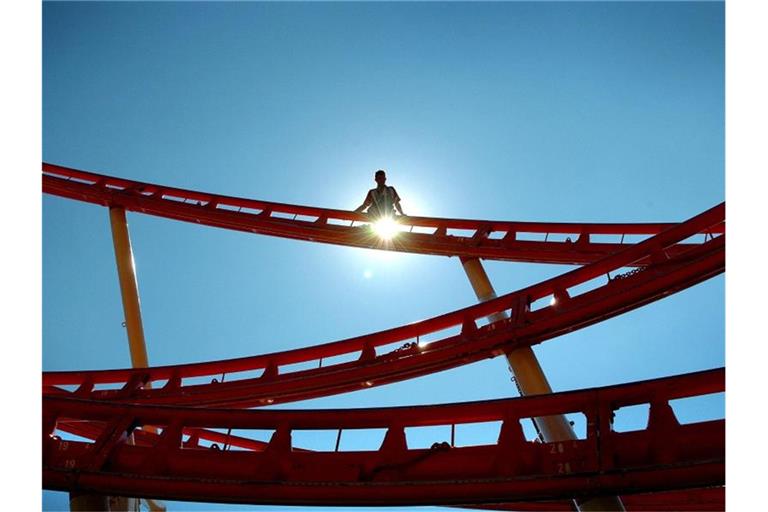 Ein Arbeiter steht auf einer Schiene der "Olympia-Looping"-Achterbahn während des Aufbaus. Foto: Daniel Karmann/dpa/Archivbild