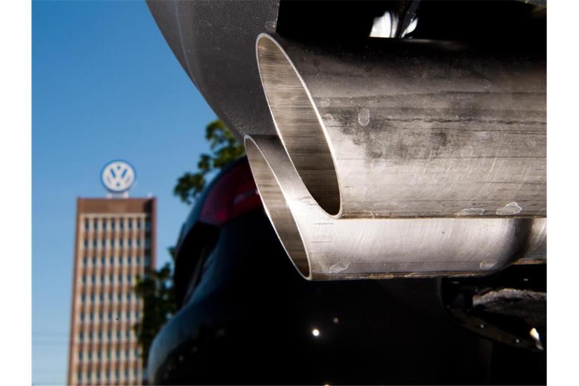 Entschädigungszahlungen - VW einigt sich mit 235.000 Kunden Ein Auspuff eines Volkswagens auf einem Mitarbeiterparkplatz - im Hintergrund Verwaltungshochhaus des VW-Werks. Foto: Julian Stratenschulte/dpa