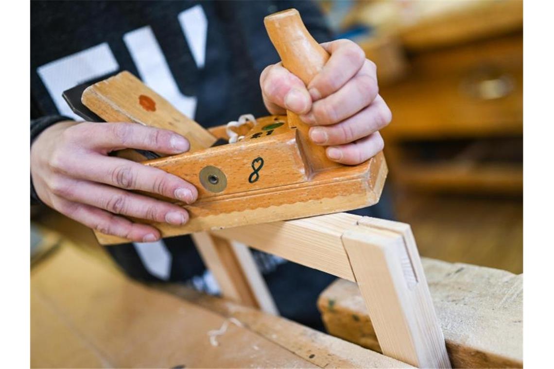 Ein Auszubildender im Schreiner-Handwerk arbeitet in einem Ausbildungszentrum mit dem Hobel an seinem Werkstück. Foto: Felix Kästle/dpa/Archivbild