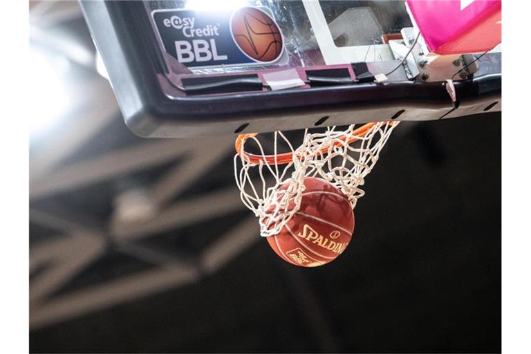 Ein Basketball fällt durch das Netz im Korb. Foto: Matthias Balk/dpa/Archivbild
