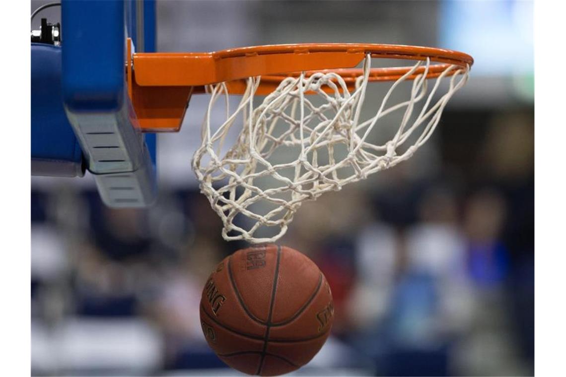 Ein Basketball fällt durch das Netz vom Basketballkorb. Foto: Lukas Schulze/dpa/Symbolbild