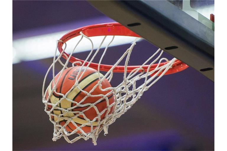 Ein Basketball im Korb. Foto: picture alliance/dpa/Archivbild