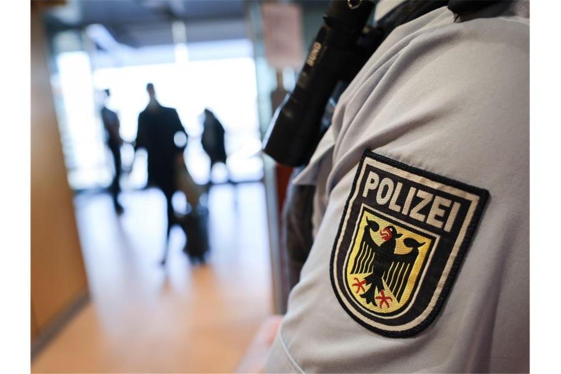 Ein Beamter der Bundespolizei kontrolliert Reisende. Foto: Christian Charisius/dpa/Symbolbild