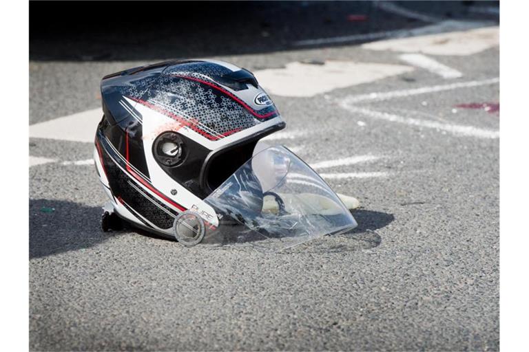Ein beschädigter Motorradhelm liegt nach einem Unfall auf einer Straße. Foto: Julian Stratenschulte/Archivbild