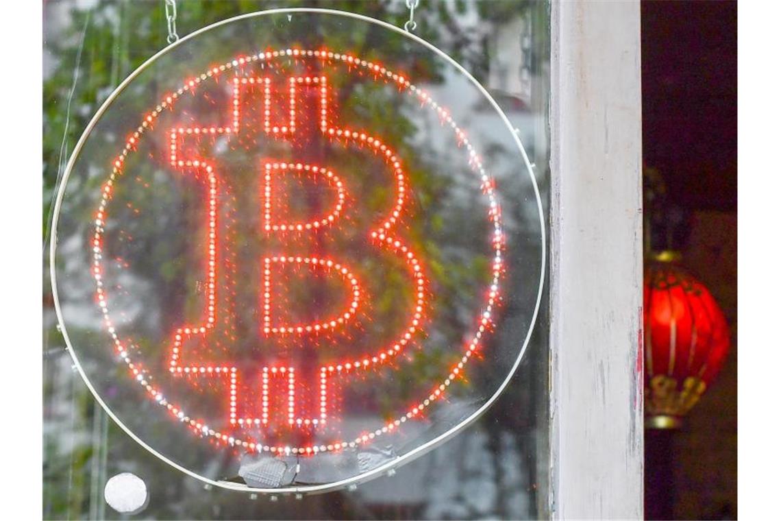 Ein Bitcoin-Logo hängt im Schaufenster. Foto: Jens Kalaene/ZB/dpa/Symbolbild