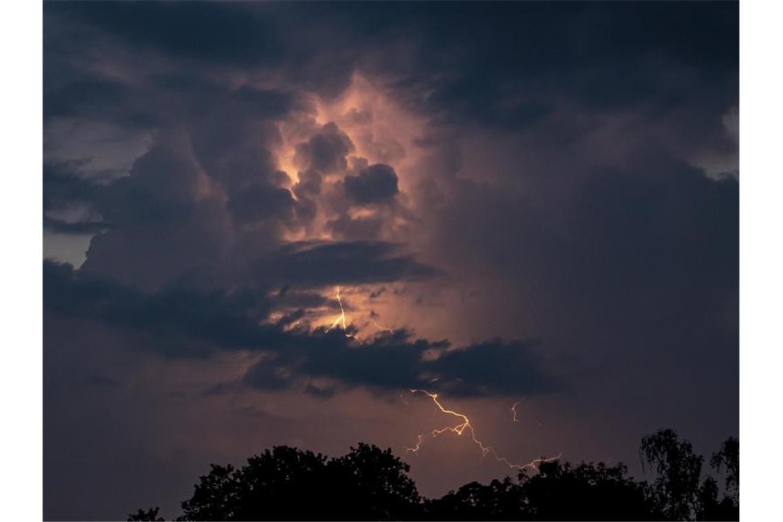 Ein Blitz hellt hinter dunklen Wolken auf. Foto: Fabian Sommer/dpa/Symbolbild