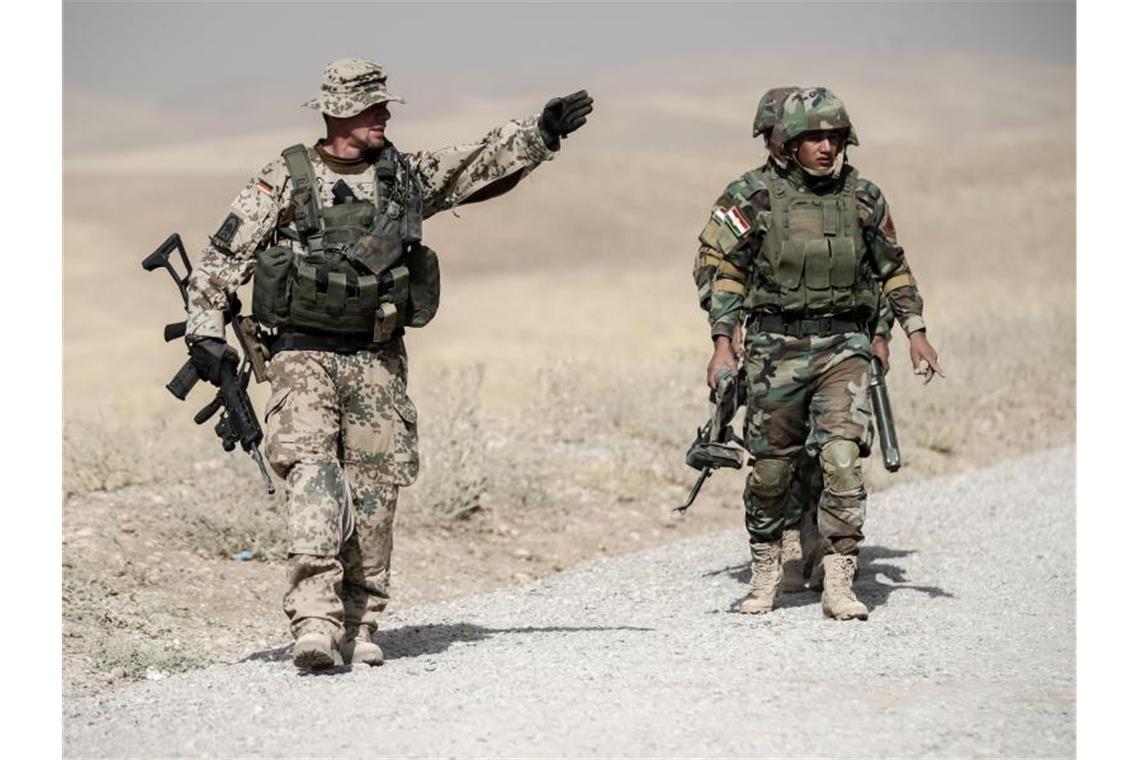 Spannungen am Golf: Bundeswehr setzt Ausbildung im Irak aus Ein Bundeswehrsoldat und kurdische Peshmerga im irakischen Erbil. Foto: Michael Kappeler/Archiv
