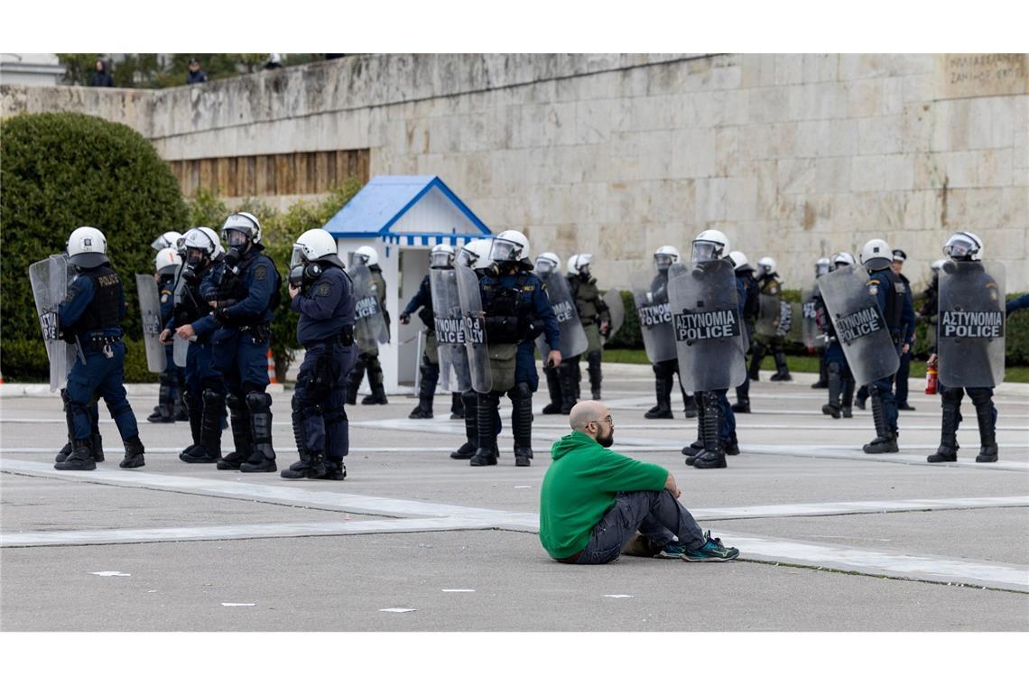 Ein Demonstrant sitzt während eines 24-stündigen Streiks in der Innenstadt von Athen vor Polizisten. Mehrere große Gewerkschaften hatten dazu aufgerufen, für höhere Löhne zu protestieren und an das schwere Zugunglück mit 57 Toten vor einem Jahr zu erinnern.