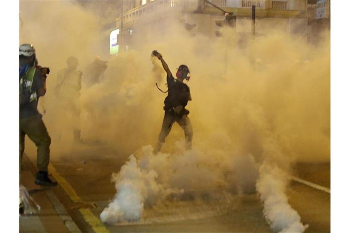 Ein Demonstrant wirft bei einer Konfrontation mit der Polizei einen Tränengasbehälter zurück. Foto: Vincent Thian/AP