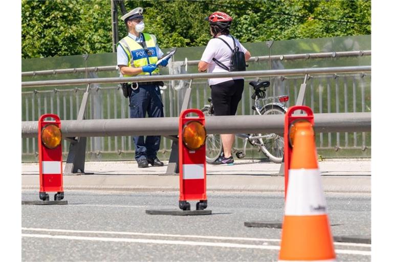 Ein deutscher Bundespolizist kontrolliert im Mai eine Fahrradfahrerin am bayerischen Grenzübergang Freilassing zwischen Deutschland und Österreich. Foto: Peter Kneffel/dpa