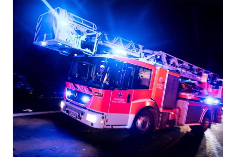 Ein Drehleiterwagen der Feuerwehr fährt mit Blaulicht über eine Straße. Foto: Marcel Kusch/dpa/Symbolbild