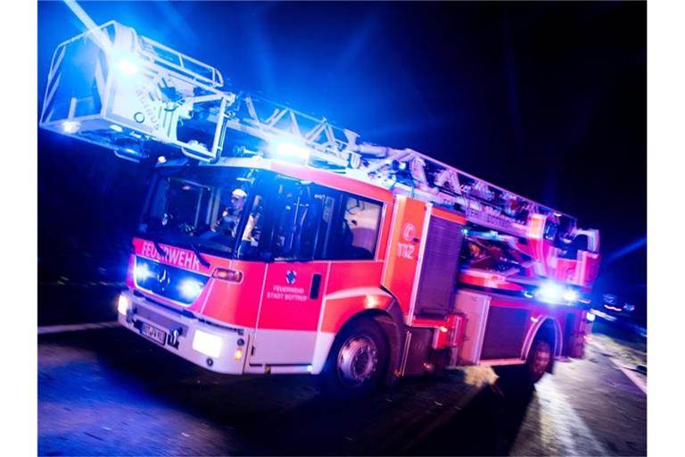 Ein Drehleiterwagen der Feuerwehr fährt mit Blaulicht an einer Unfallstelle vorbei. Foto: Marcel Kusch/dpa/Illustration