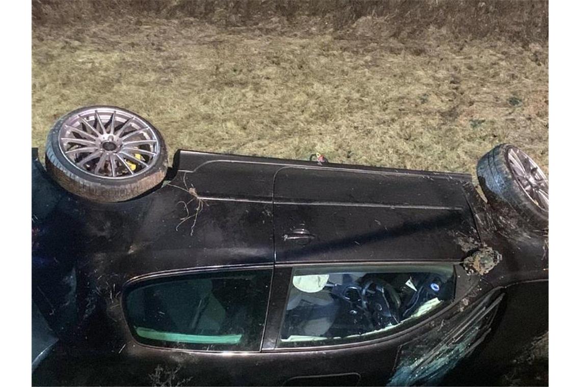 Auto stürzt in Wasserbecken: Fahrer lässt Verletzte zurück Ein Fahrzeug liegt, nachdem es sich überschlagen hat, auf dem Dach in einem Wasserrückhaltebecken. Foto: Schulz/SDMG/dpa