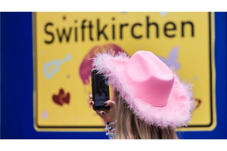 Ein Fan fotografiert vor dem Konzert der Sängerin Taylor Swift in Gelsenkirchen ein "Swiftkirchen"-Schild. Während des Konzerts am Abend zog der Datenverbrauch in den Handynetzen in der Veltins Arena kräftig an.