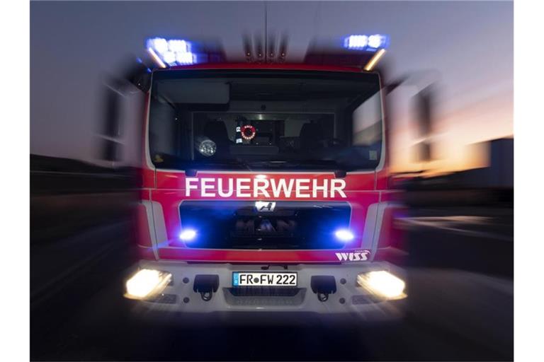 Ein Feuerwehrfahrzeug steht mit eingeschaltetem Blaulicht auf einer Straße. Foto: Patrick Seeger/dpa/Symbolbild