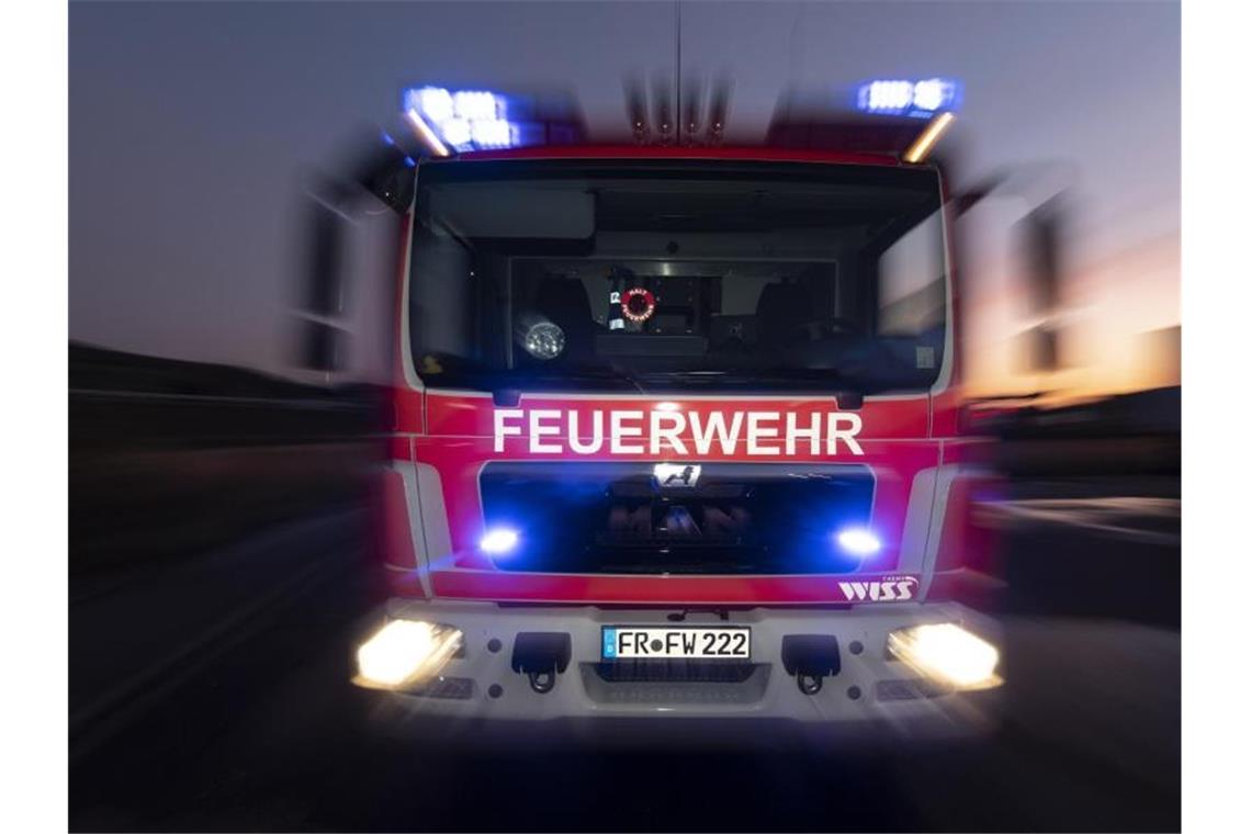 Ein Feuerwehrfahrzeug steht mit eingeschaltetem Blaulicht auf einer Straße. Foto: Patrick Seeger/dpa/Symbolbild